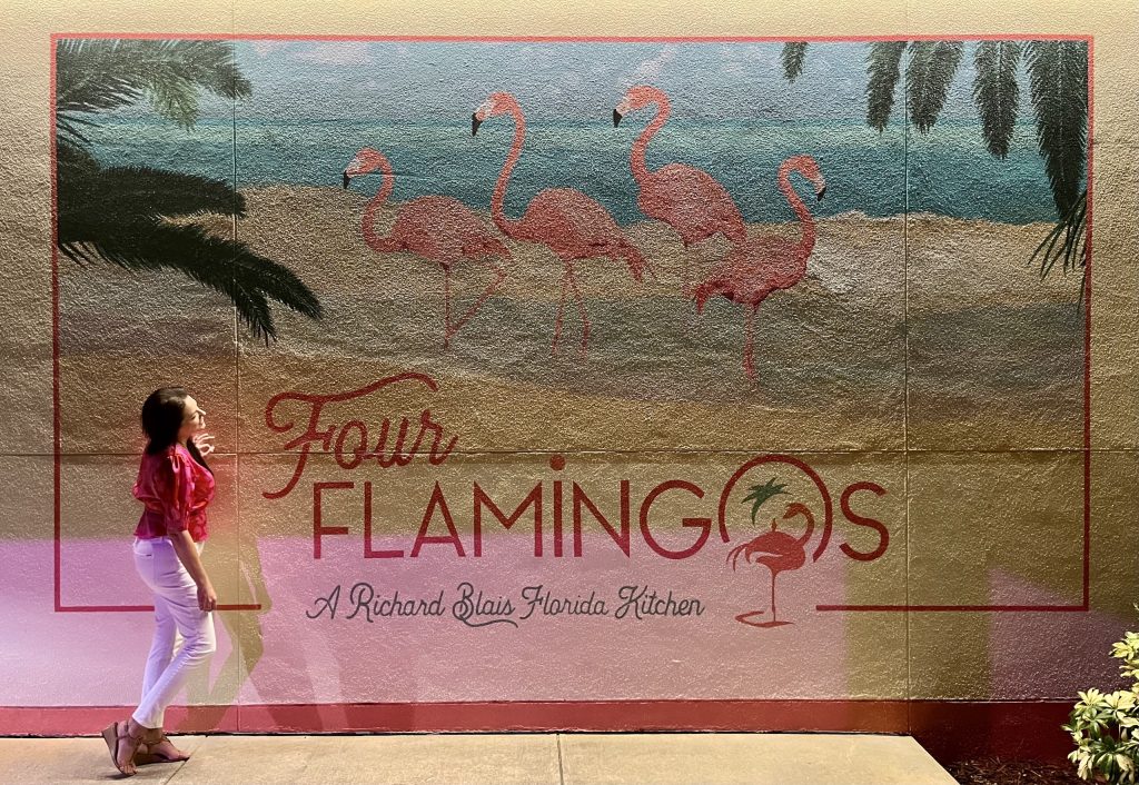 woman looking up at a mural of four flamingos