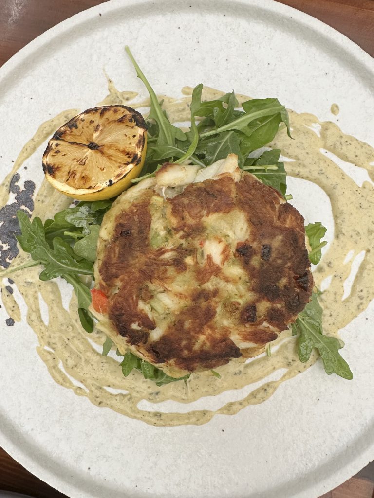 crab cake with sauce and arugula on a plate