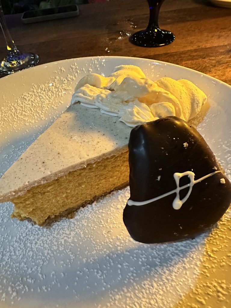 a slice of pumpkin cheesecake with a chocolate covered pilgrim hat shaped cookie
